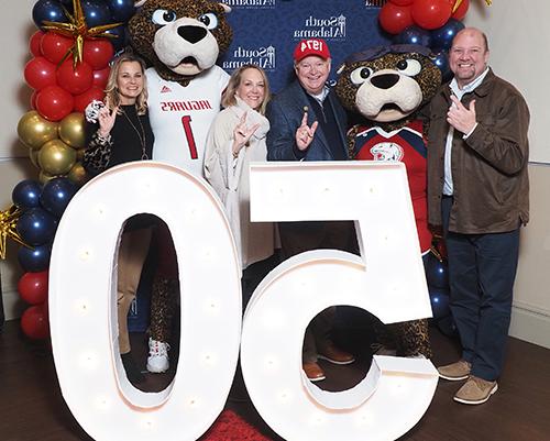 President Bonner and his wife and Vice President Kent and her husband with Southpaw and Ms. Pawla behind 50th anniversary sign.